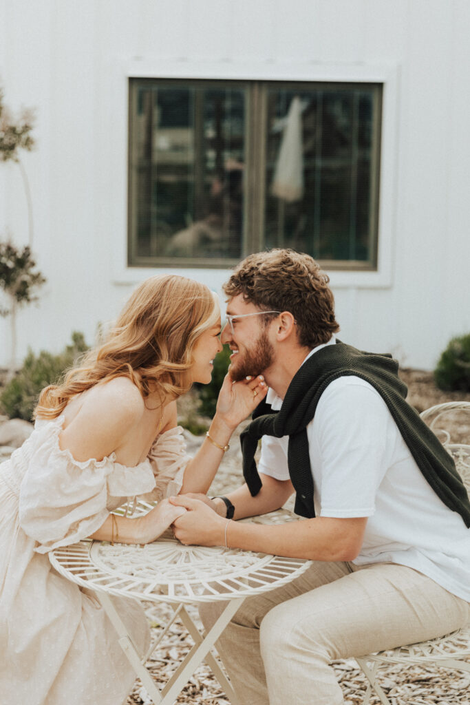 couple sitting at a café table during a french inspired engagement session with soft natural light