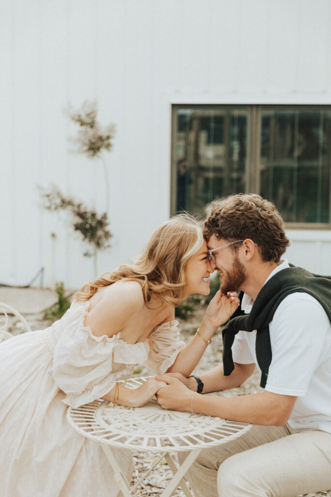 european inspired engagement moment with couple sitting outside a white cottage café