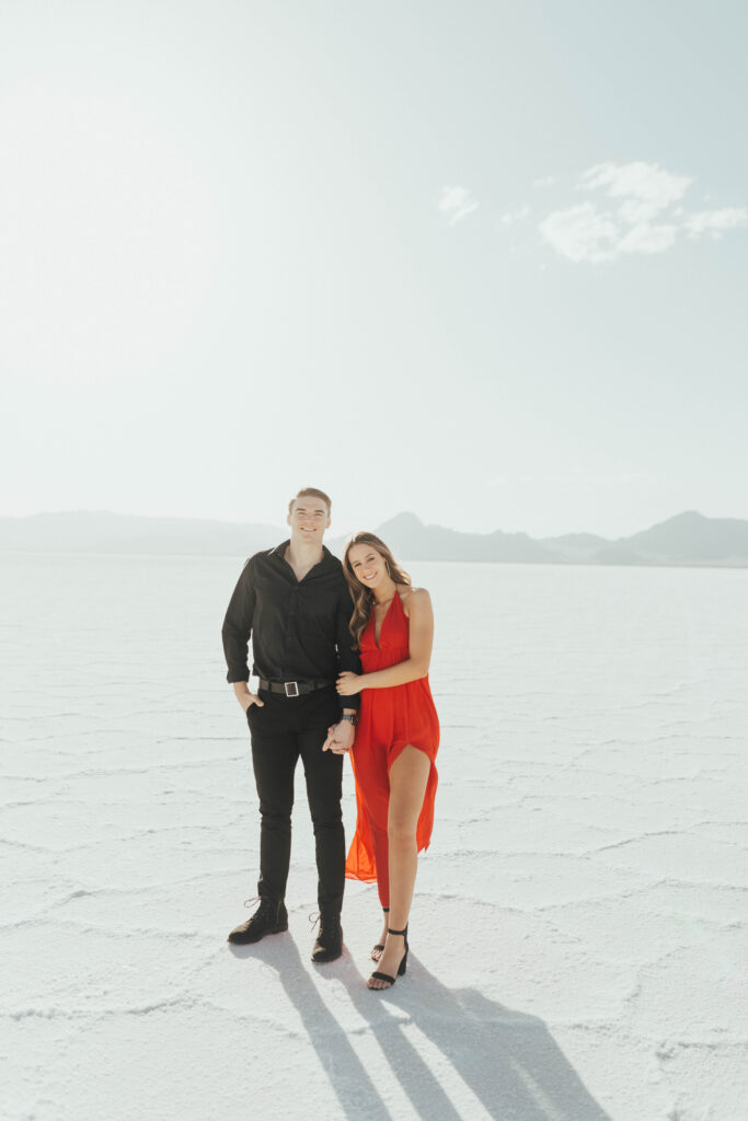 Couple dancing across the Salt Flats during bold red dress engagement portraits.