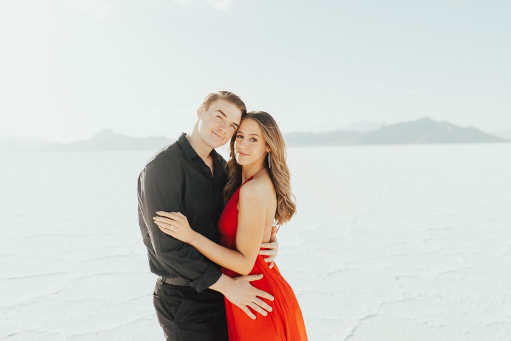 Classic, timeless portrait of groom-to-be holidng his bride-to-be close and looking at camera.