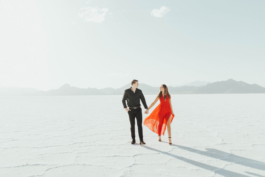 Bride-to-be in bold red dress walking across the Salt Flats during destination engagements.