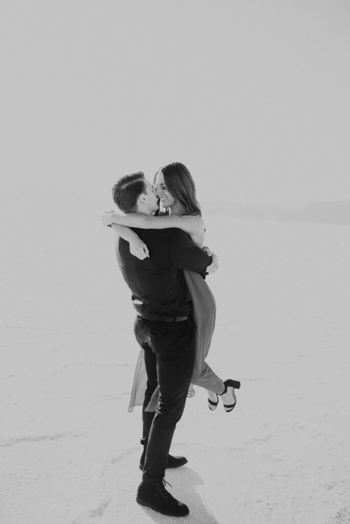 Black and White fine art image with couple doing a lift prompt at their bonneville salt flats engagements