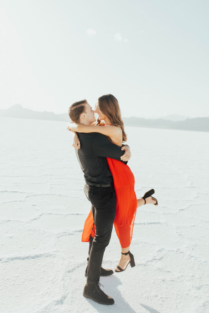 Romantic lift pose with red dress flowing at Bonneville Salt Flats.