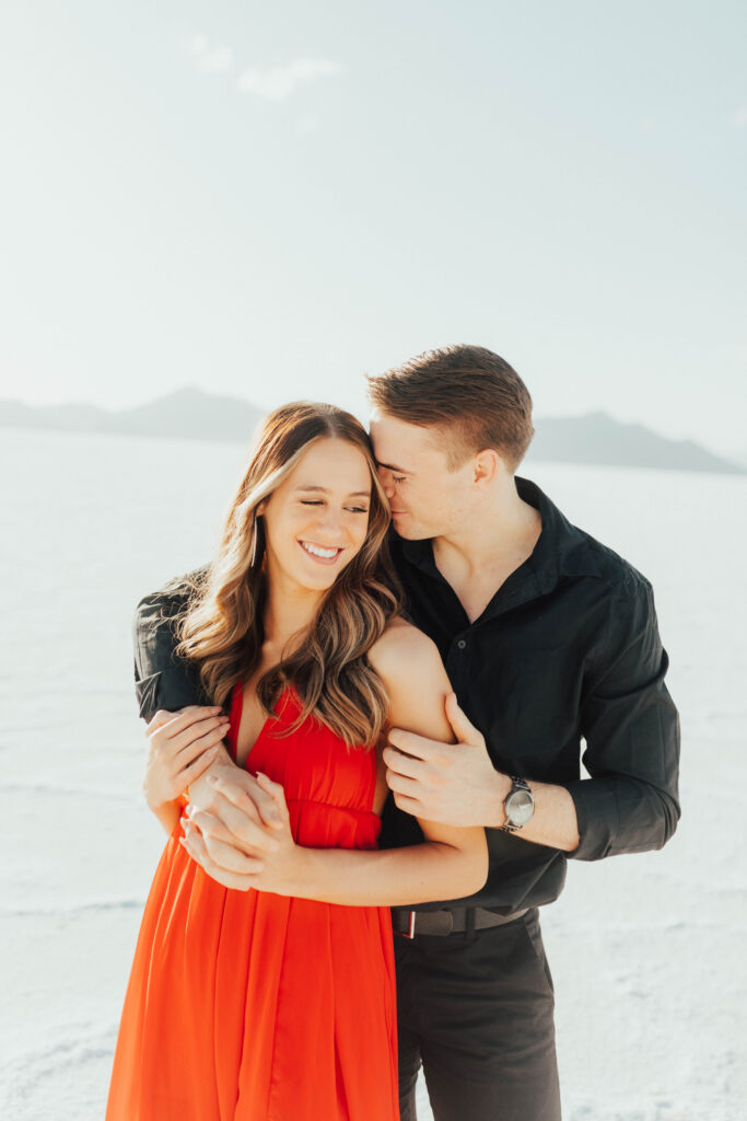 Bride glancing over shoulder in red dress during Salt Flats engagements.