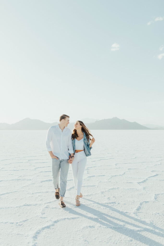Couple walking hand in hand across the Salt Flats during golden hour portraits.