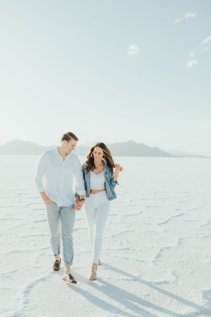 Couple walking together during Salt Flats engagements in neutral white outfits.