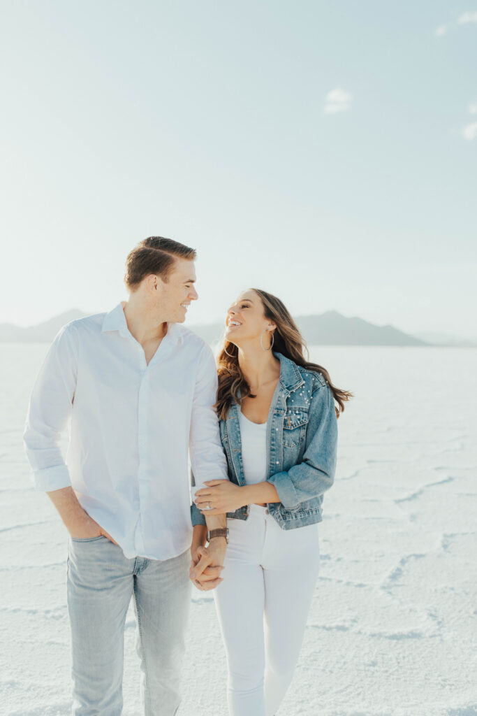 Bride in white jeans and tank laughing during Salt Flats engagement photos.