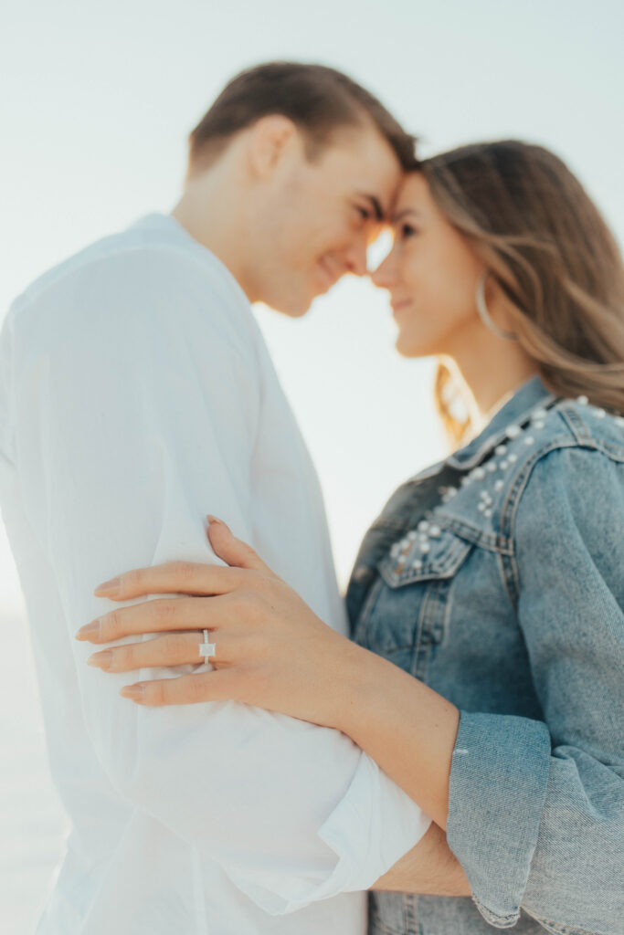 Close-up of an engagement ring as a couple leans forehead to forehead during their Salt Flats engagement session, with soft golden light and joyful intimacy.