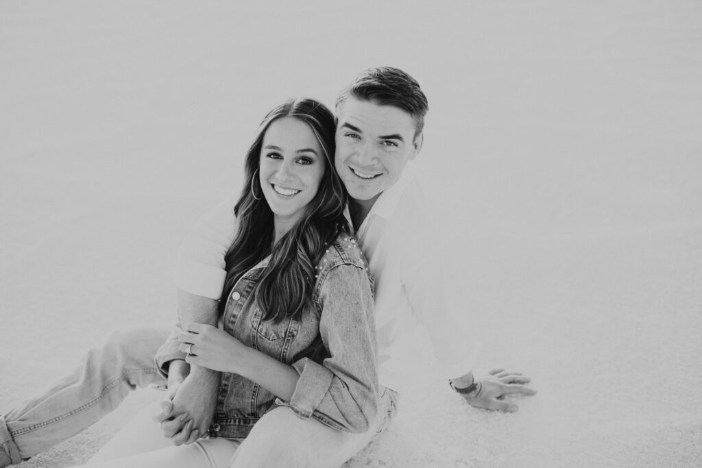 Black and white portrait of couple sitting together during destination Salt Flats engagements, creating a timeless and romantic moment.