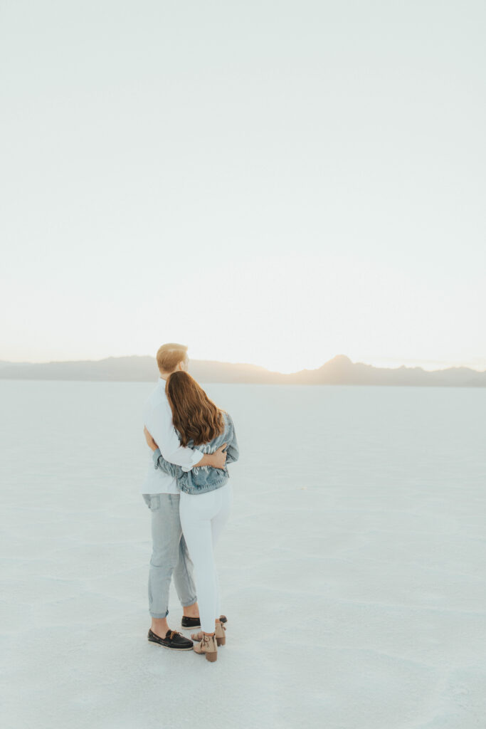 Quiet, intimate embrace during Salt Flats sunset engagement photos.