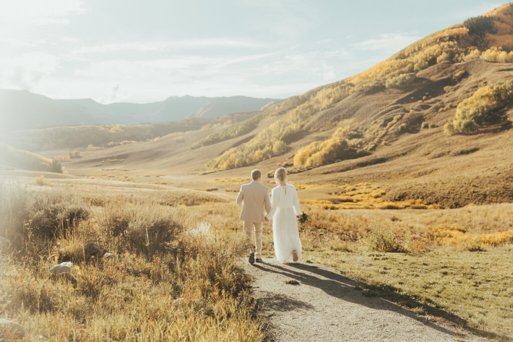 bride and groom walking through golden fall mountains during crested butte wedding portraits